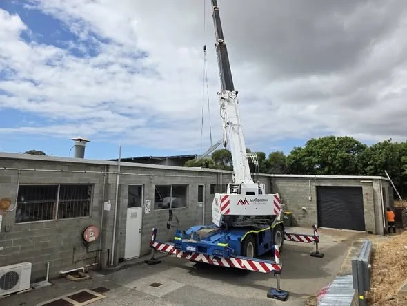 Mobile crane lifting materials onto the commercial roof