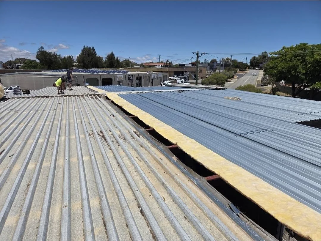 Commercial roof part way through re-sheeting with anticon insulation visible