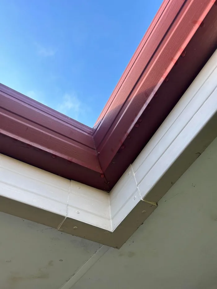 Newly installed red gutter and white fascia corner
